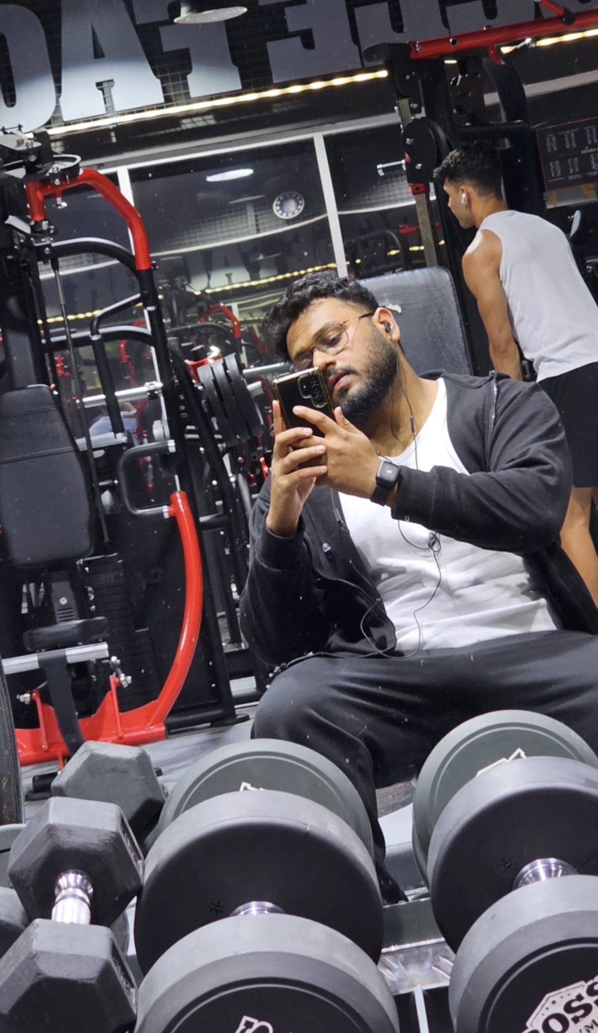 Aman sitting between dumbbells after a gym session